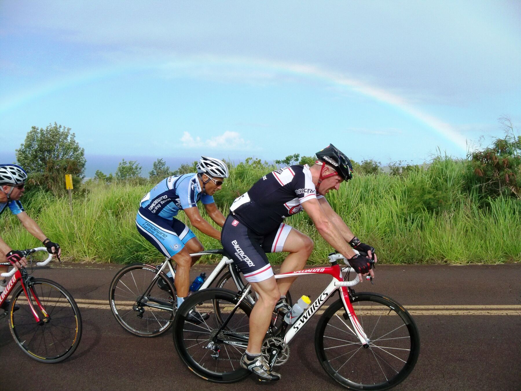 Two riders racing beneath a rainbow