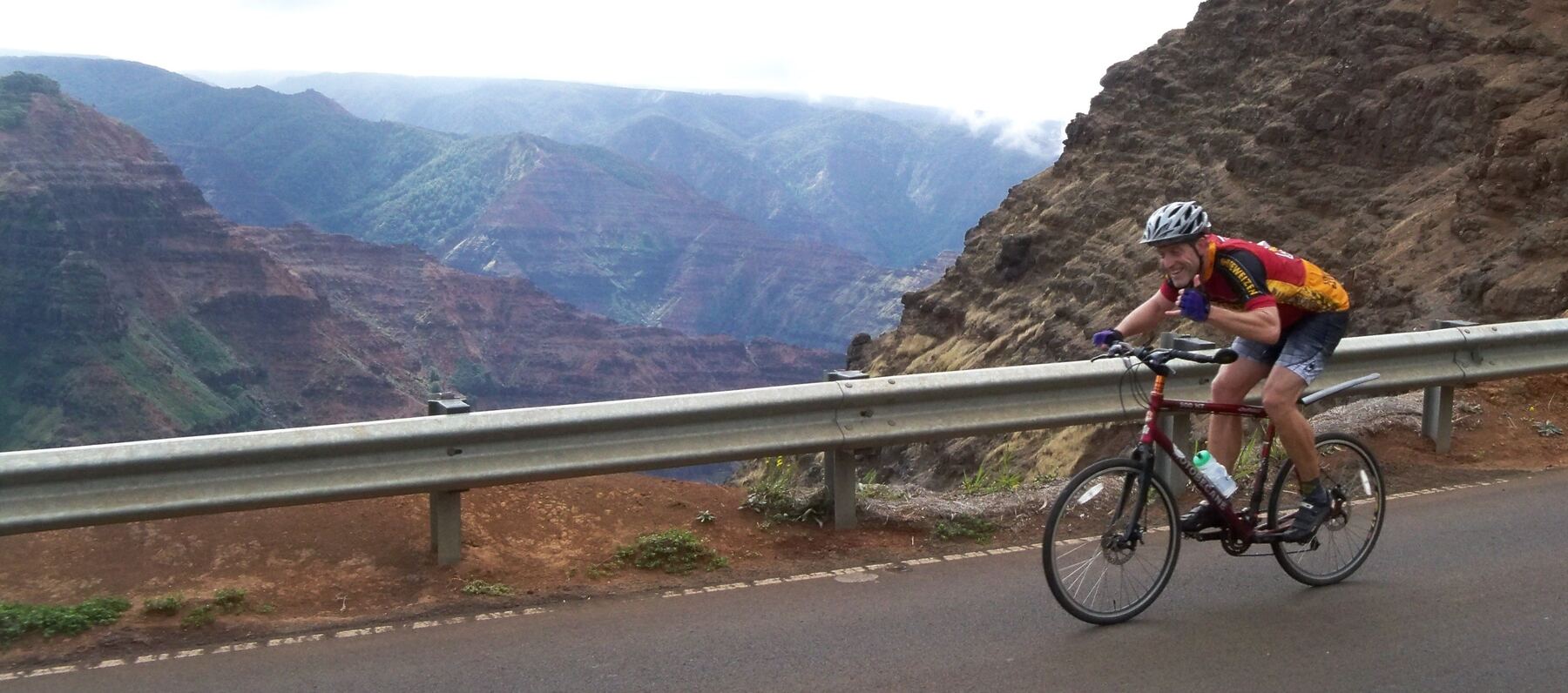 Cyclist throwing a shaka above Waimea Canyon